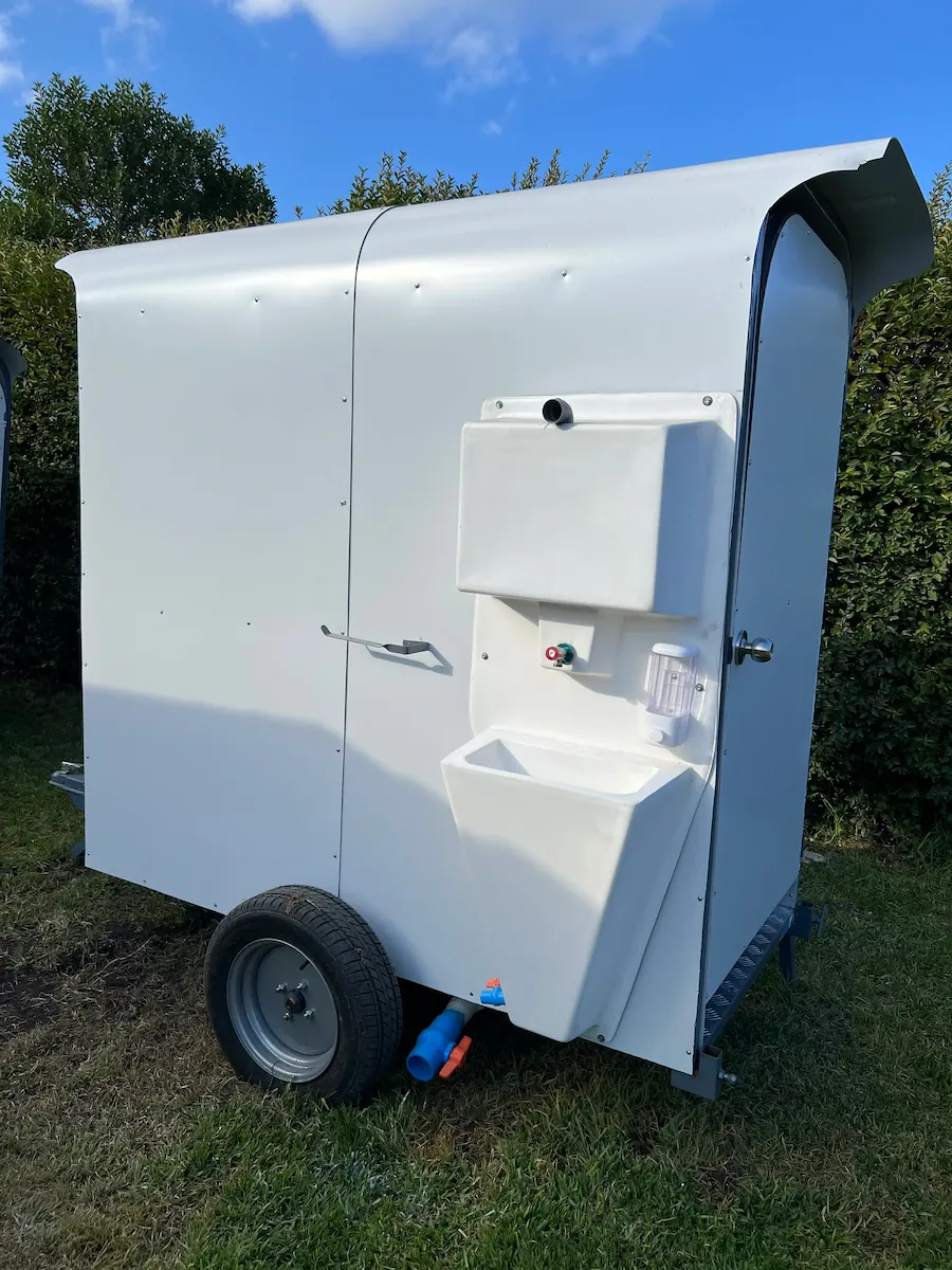 Vista trasera izquierda del baño químico doble de arrastre